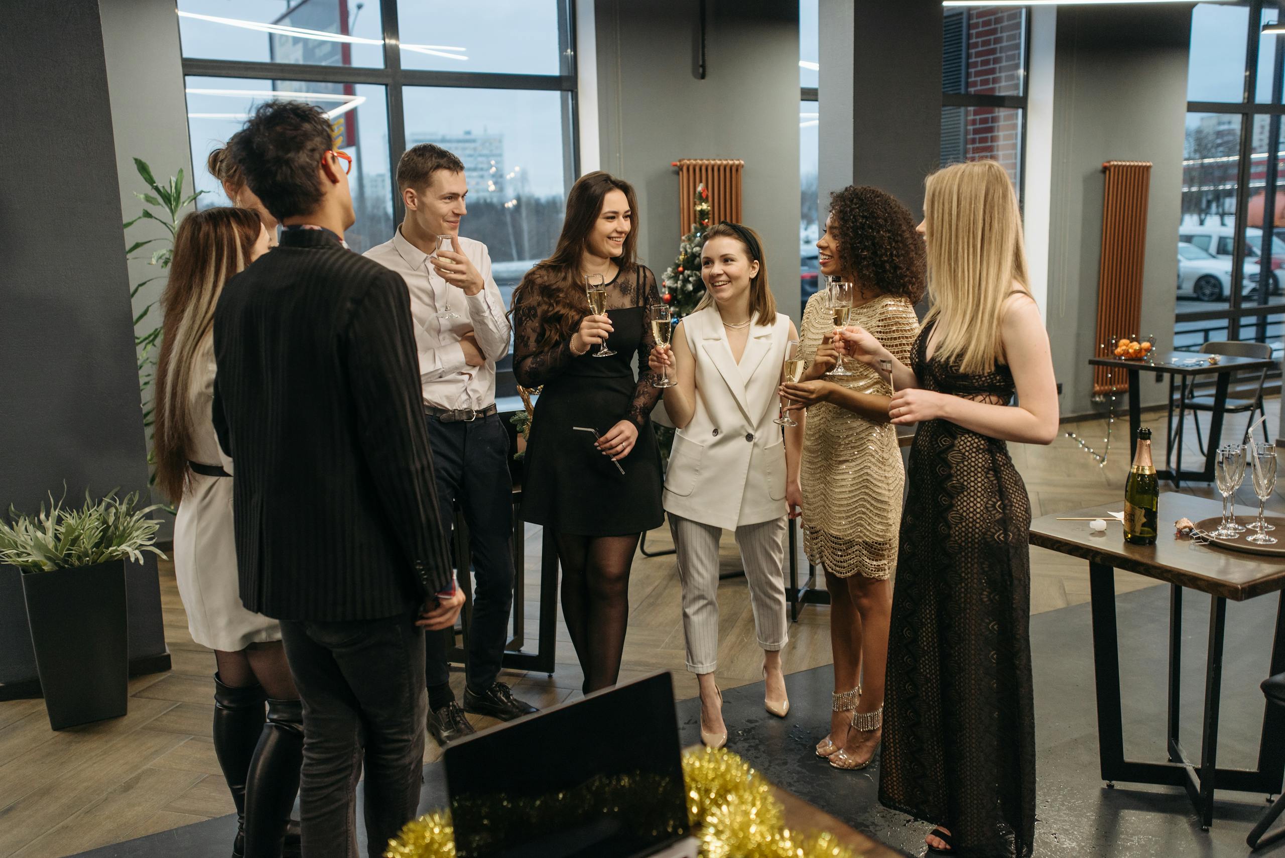 A diverse group of colleagues celebrating at an office party with drinks and laughter.